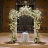 Tall white floral arch with matching column arrangements framing a small draped table