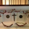 White casket with red rose garland and a crucifix inside