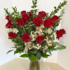 Red roses and white filler flowers in a clear glass vase