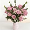 Pink roses arranged in a patterned vase with small white filler flowers