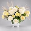 White roses and pale yellow carnations in a white vase with airy pampas grass