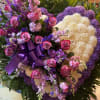 Large purple and pink floral standing arrangement with a ribbon bow