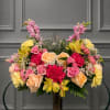 Large floral arrangement with pink, peach, and yellow flowers in a vase