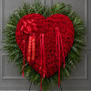 Heart-shaped red rose wreath with red ribbons on a stand