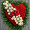 Heart-shaped red floral tribute with white roses and a red bow on an easel