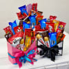 Two gift boxes filled with assorted candy bars and snacks, tied with ribbons.