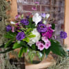 Purple and white flowers arranged in a clear glass vase