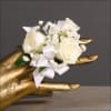 White rose corsage with baby's breath and ribbon on a gold hand display