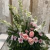 Pink roses and white flowers arranged around a glass cross