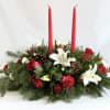 Holiday centerpiece with red candles, white lilies, and pinecones