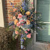 Tall standing floral spray with pink and peach roses and blue flowers
