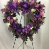 Heart-shaped floral wreath with purple and pink flowers on a stand