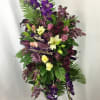 Tall funeral spray with purple flowers and ribbons reading Father and Grandfather