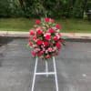 Standing floral wreath of pink and red flowers on a white easel