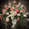 Pink roses and carnations in a white vase with a cream ribbon