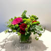 Mixed floral arrangement with red roses and a pink gerbera daisy in a glass vase
