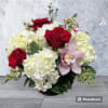 Bouquet of red roses, white hydrangeas, and a pink orchid in a low vase