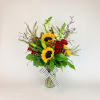 Sunflowers and red roses in a glass vase with a striped ribbon