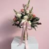 Pink and white rose bouquet in a glass vase with a satin ribbon