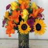 Bouquet of sunflowers, orange lilies, and purple flowers in a glass vase