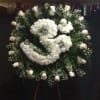 Large white funeral wreath with roses and clustered blooms