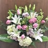 Pink roses and white lilies arranged in a clear glass vase