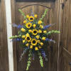 Standing floral spray with yellow sunflowers and roses accented by blue flowers
