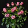 Pink roses arranged in a glass vase with greenery