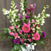Pink and white mixed flower arrangement in a glass vase with a white ribbon