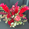 Red tropical bouquet with orchids, roses, and protea in a vase