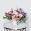 Pastel floral arrangement in a white vase with pink and purple blooms