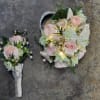 A wrist corsage and boutonniere set with light pink spray roses, white