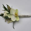 A boutonniere featuring pale yellow phaleonopsis orchids, white spray roses, clear rhinestones