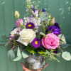 Mixed bouquet of roses and purple flowers in a glass vase