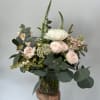 Seasonal light pink and white flowers arranged with greenery in a vase.