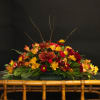 Low floral arrangement with red, yellow, and orange blooms