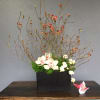 Orchid arrangement in a black rectangular container with branching stems