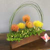 A pretty arrangement including orange tropical flowers and green plants