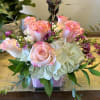 White hydrangeas with blush pink roses in a glass cube