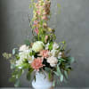 Pastel floral arrangement in a white pedestal vase with tall pink blooms