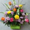 Mixed bouquet of roses and purple daisies in a green basket
