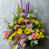 Mixed bouquet of yellow, pink, and lavender flowers in a metal bucket