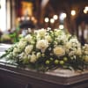 White rose casket spray on a closed casket in a softly lit chapel
