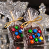 Wrapped chocolate treats topped with colorful candies and gold ribbons