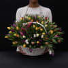 Basket of multicolored tulips held by a person