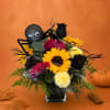 Halloween bouquet with sunflowers, black roses, and a spider decoration in a glass vase