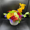 Colorful mixed flower arrangement in a gray vase with yellow orchids and red roses