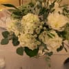 White floral centerpiece in a clear glass vase with eucalyptus