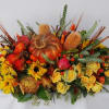 A warm fall centerpiece with roses, sunflowers, peonies, pumpkin, rose hips, banksias