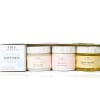 Three body care jars and a sampler box on a white shelf